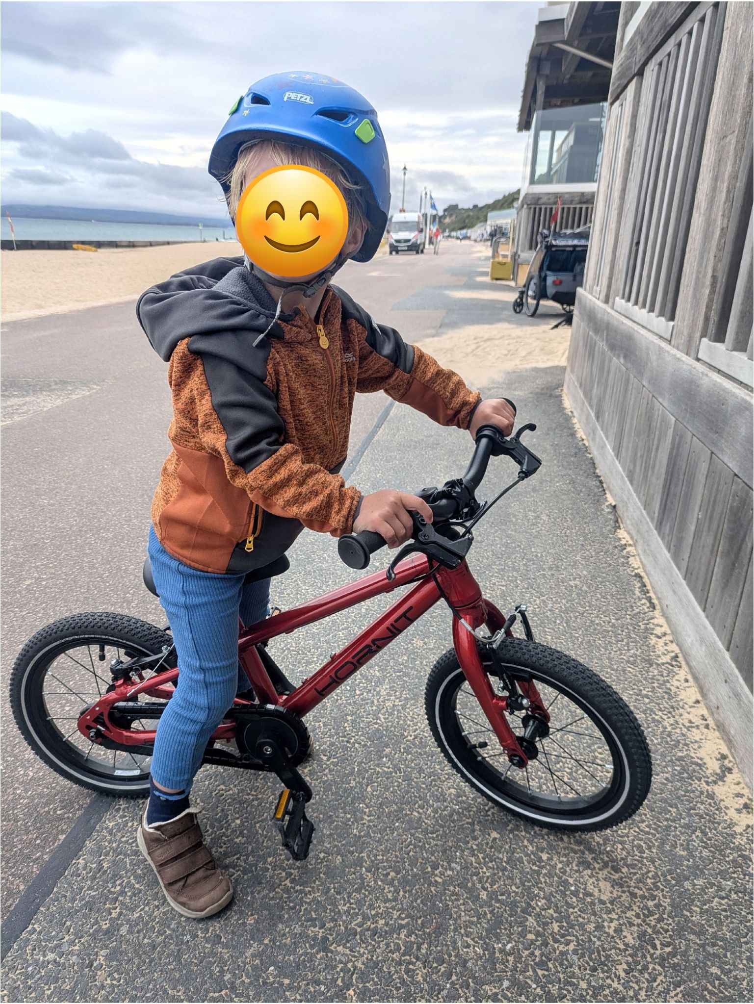Hornit HERO 14 red kids bike being ridden by a young boy by the beach