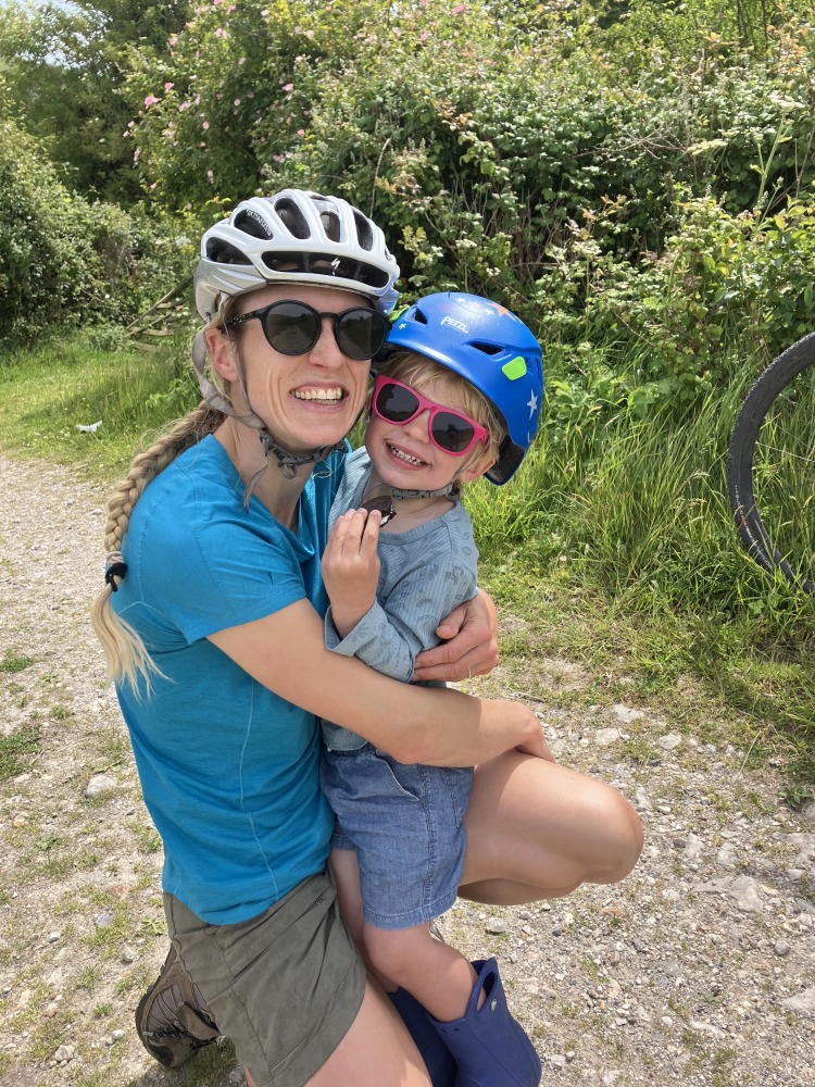 a woman holding her son both wearing bike helmets out on a family cycling day