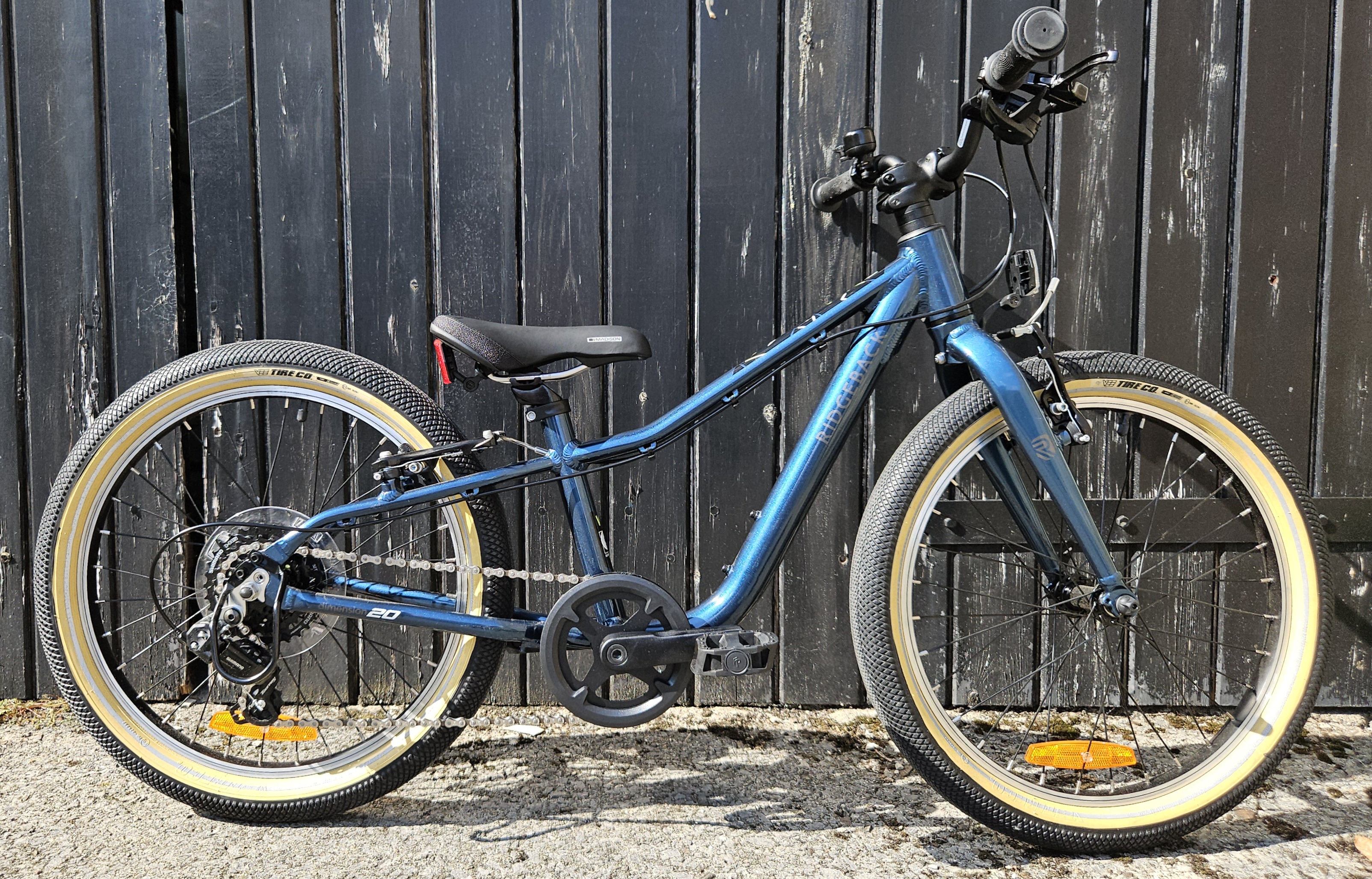 Ridgeback Dimension 20 inch kids bike leaning against a fence 