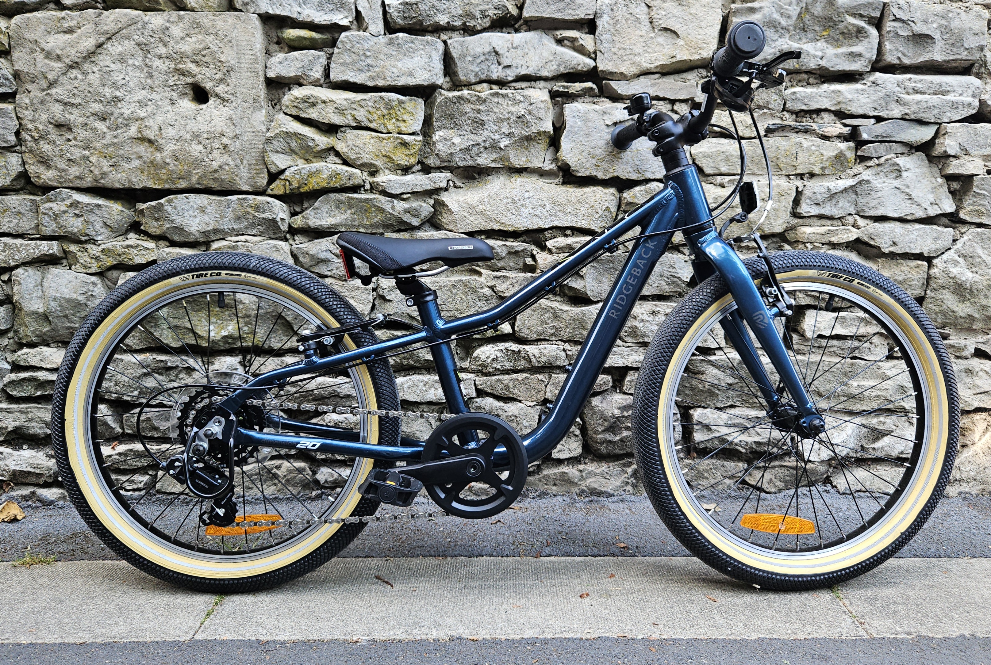 Ridgeback Dimension 20 kids bike side on leant against a stone wall