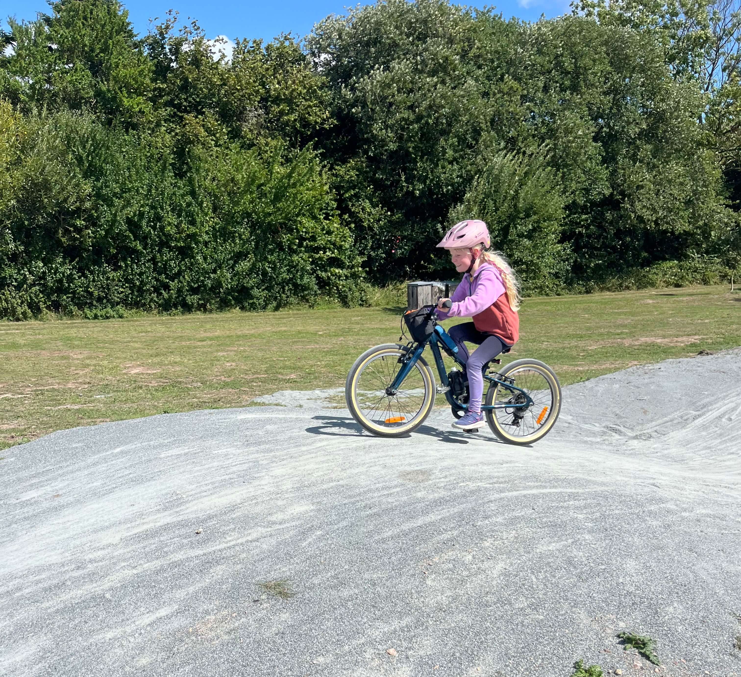 Ridgeback Dimension 20 kids bike being ridden up a gravel hill by a young girl dressed in pink