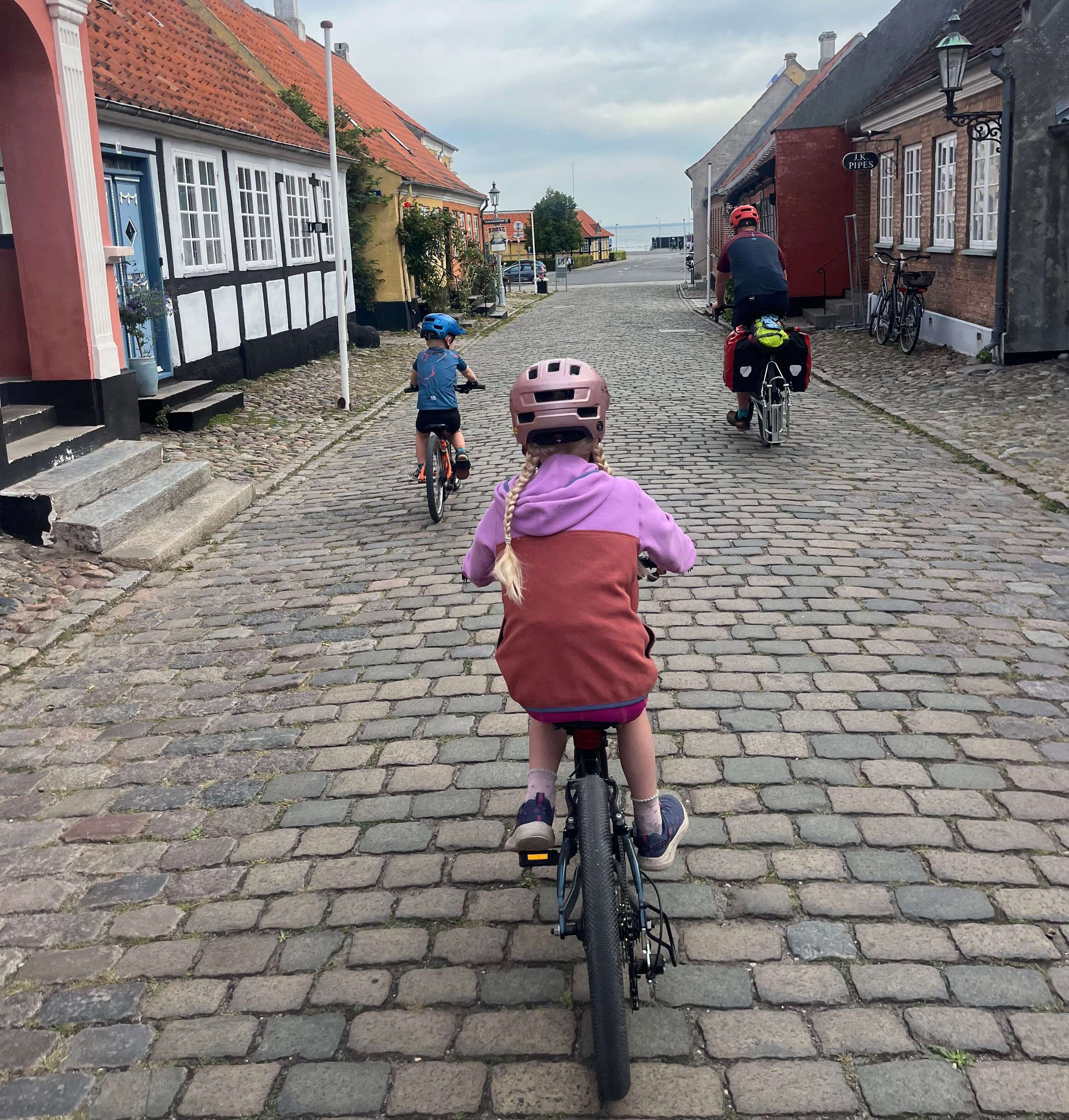 Ridgeback Dimension 20 kids bike being ridden by a young girl along a cobbles street with old fashioned houses
