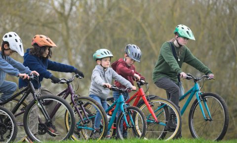 Group of children riding Ridgeback bikes in a grassy park area