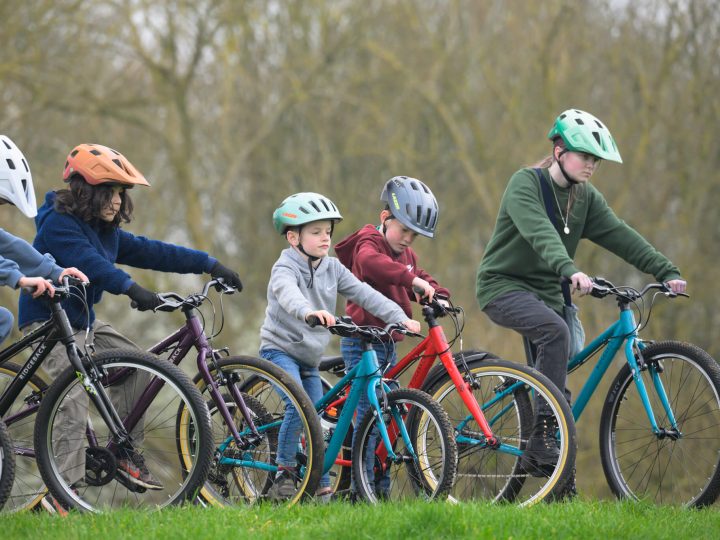 Group of children riding Ridgeback bikes in a grassy park area