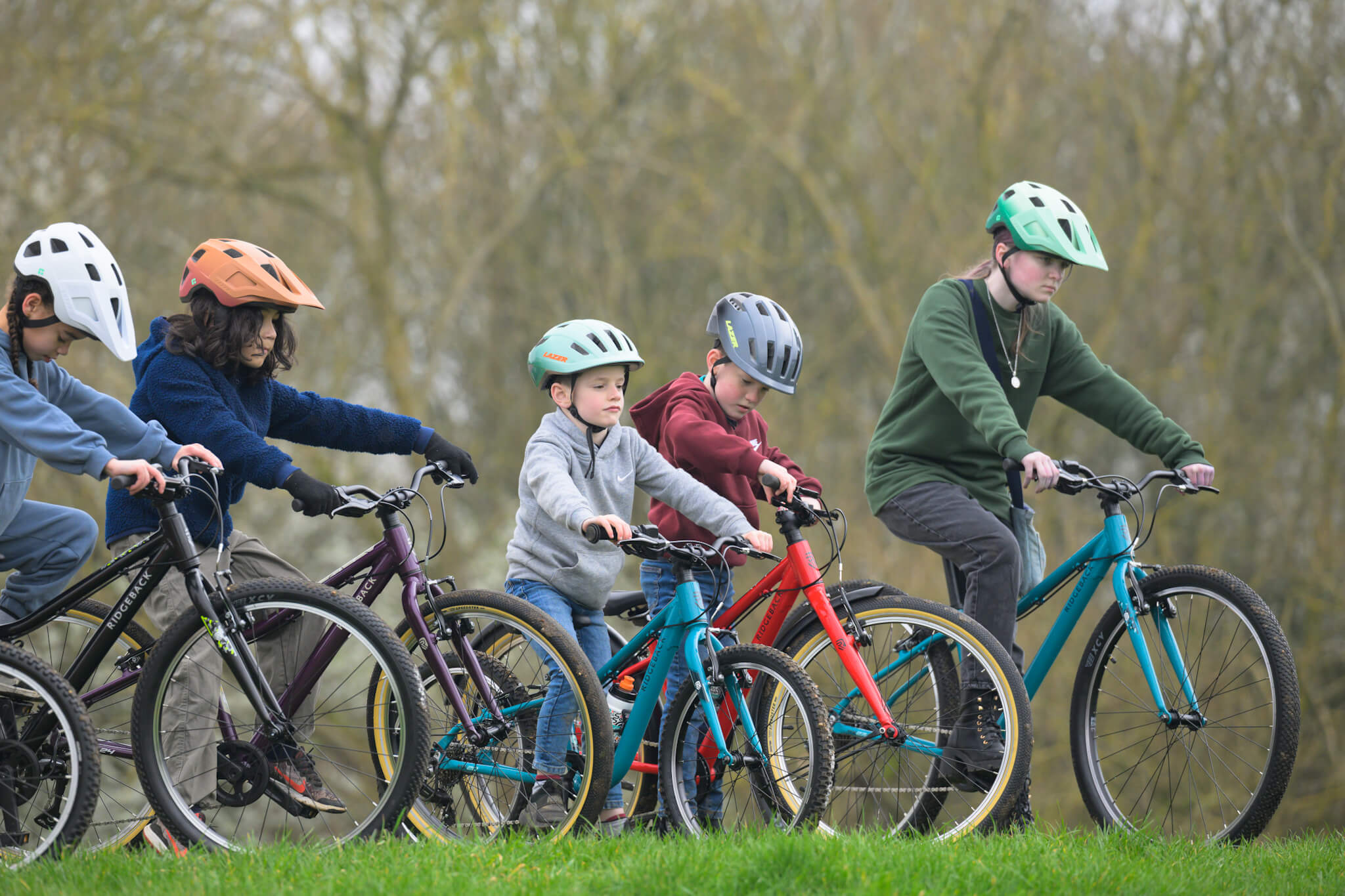 Group of children riding Ridgeback bikes in a grassy park area