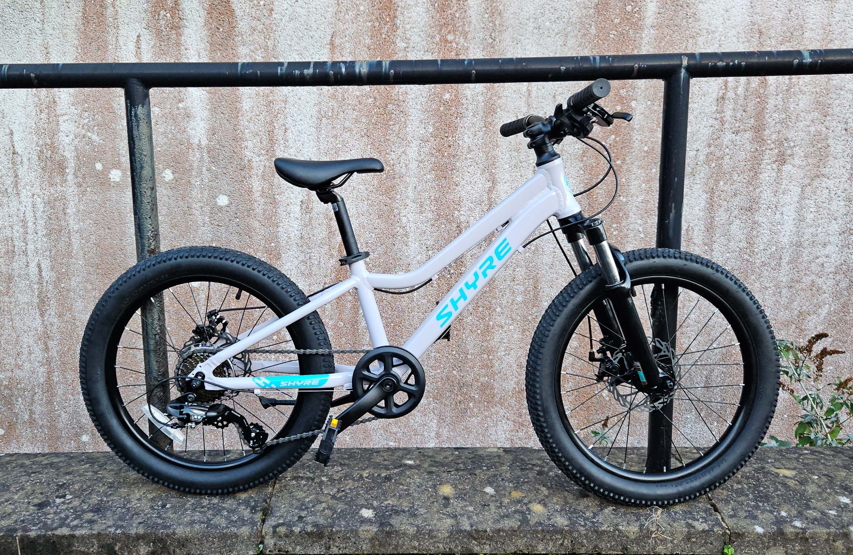 Side view of the Shyre Eastie 20 kids bike leant against a railings