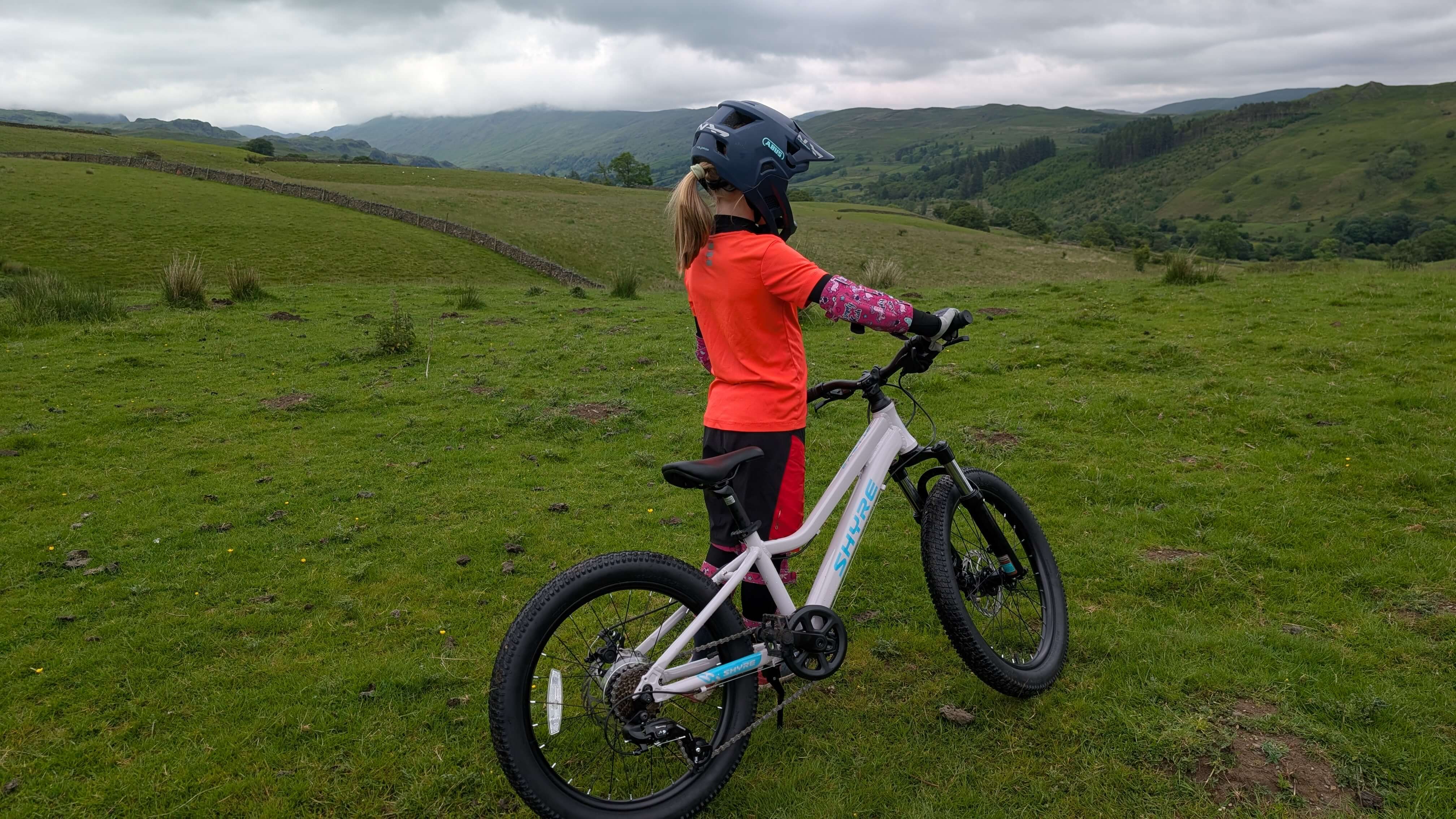 Young girl out in the countryside stood beside the Shyre Eastie 20 kids bike 