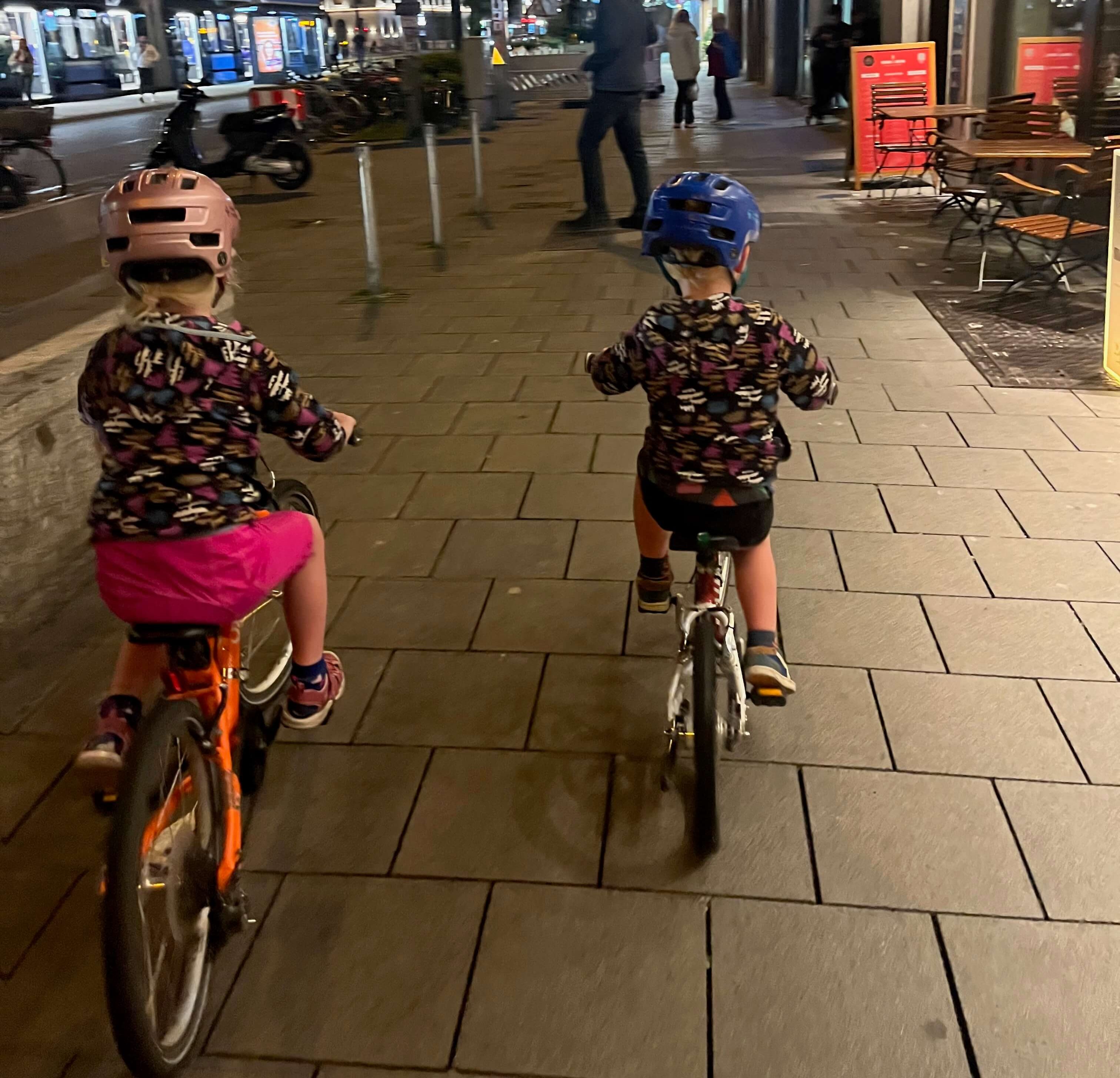 Two kids cycling at night in Munich on a family holiday