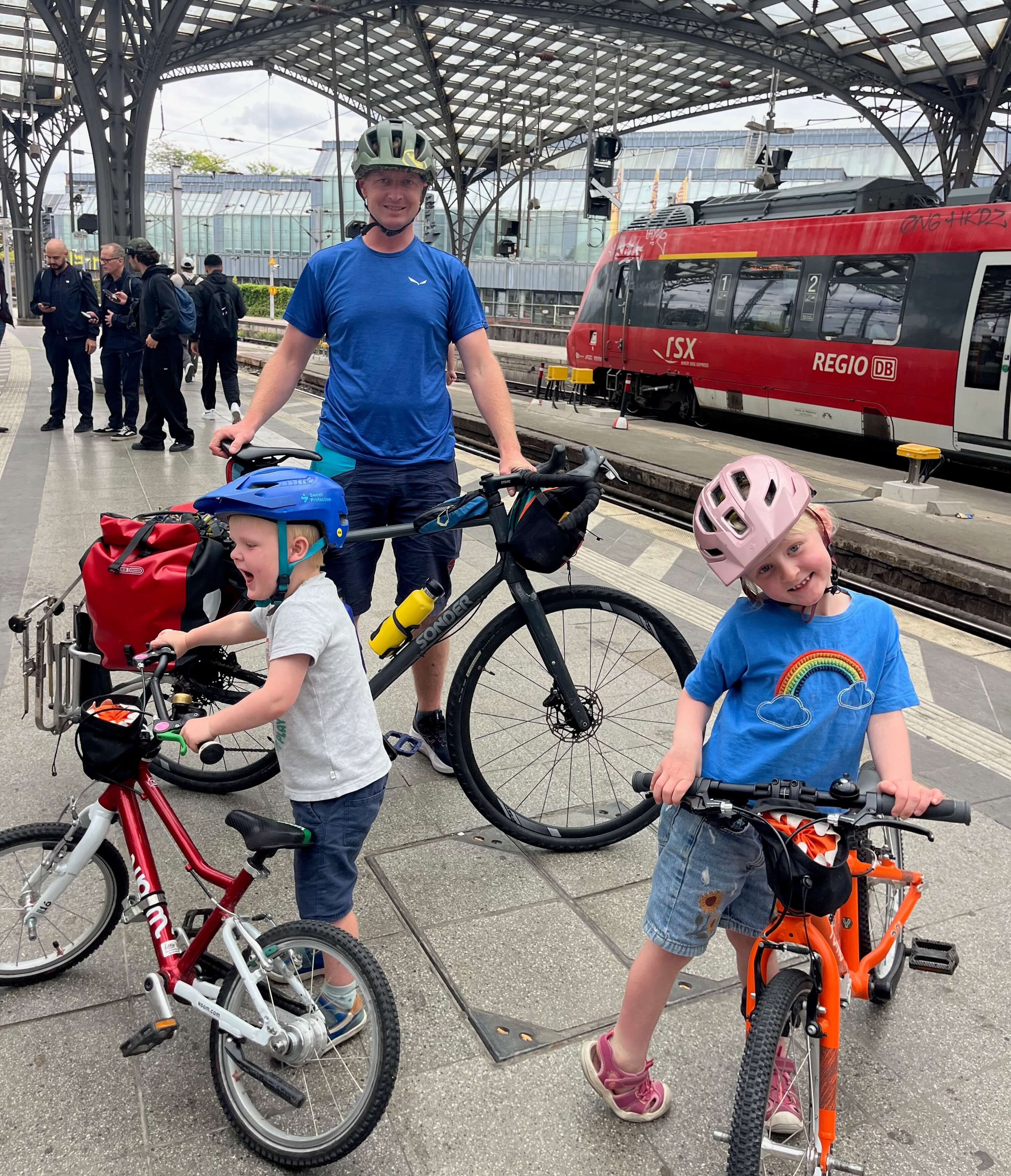 Dad and 2 kids at a train station with their bikes