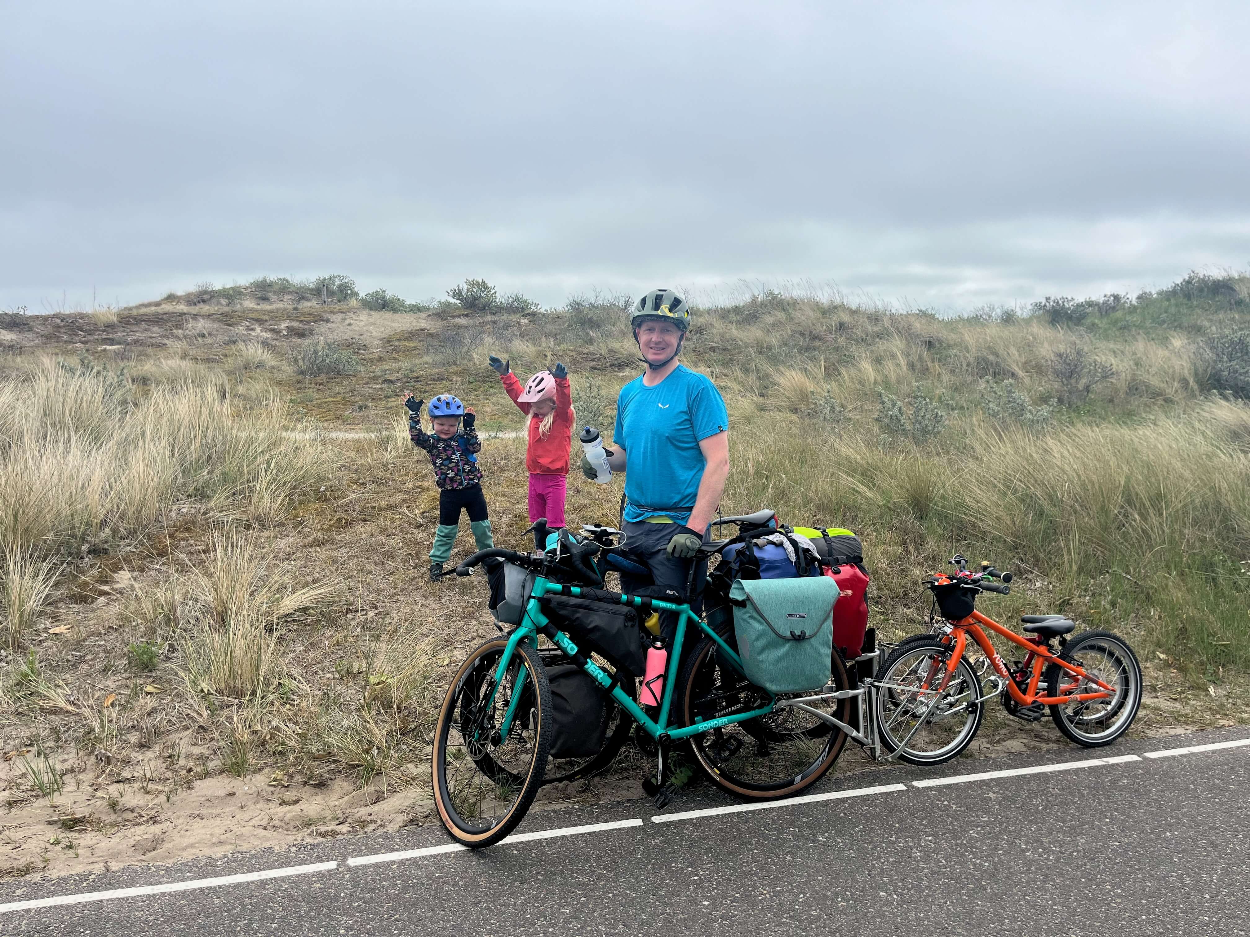 Family cycling holiday in the Netherlands - 2 children playing in the dunes beside their bikes