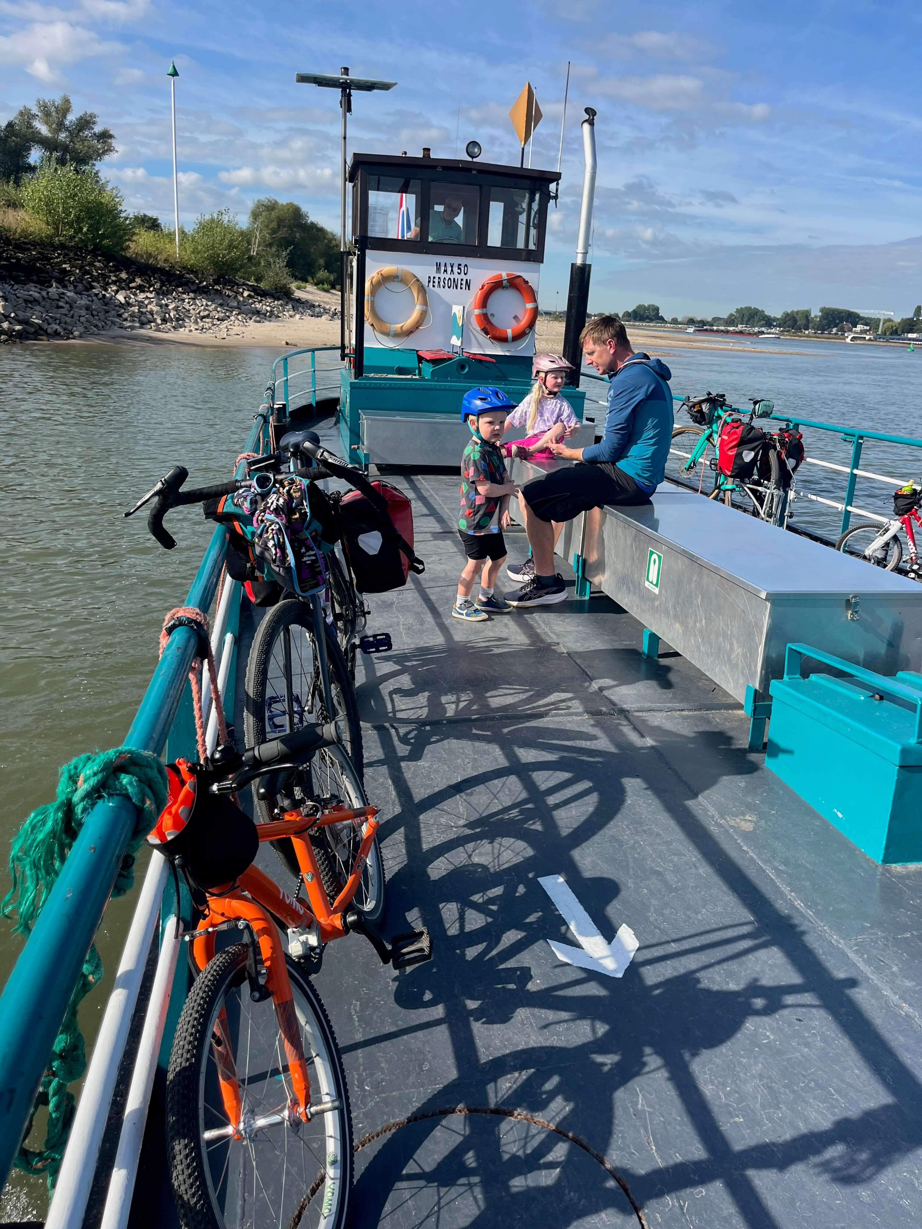 Family sat on the ferry over the Rhine with their bikes and cycling gear on a sunny day