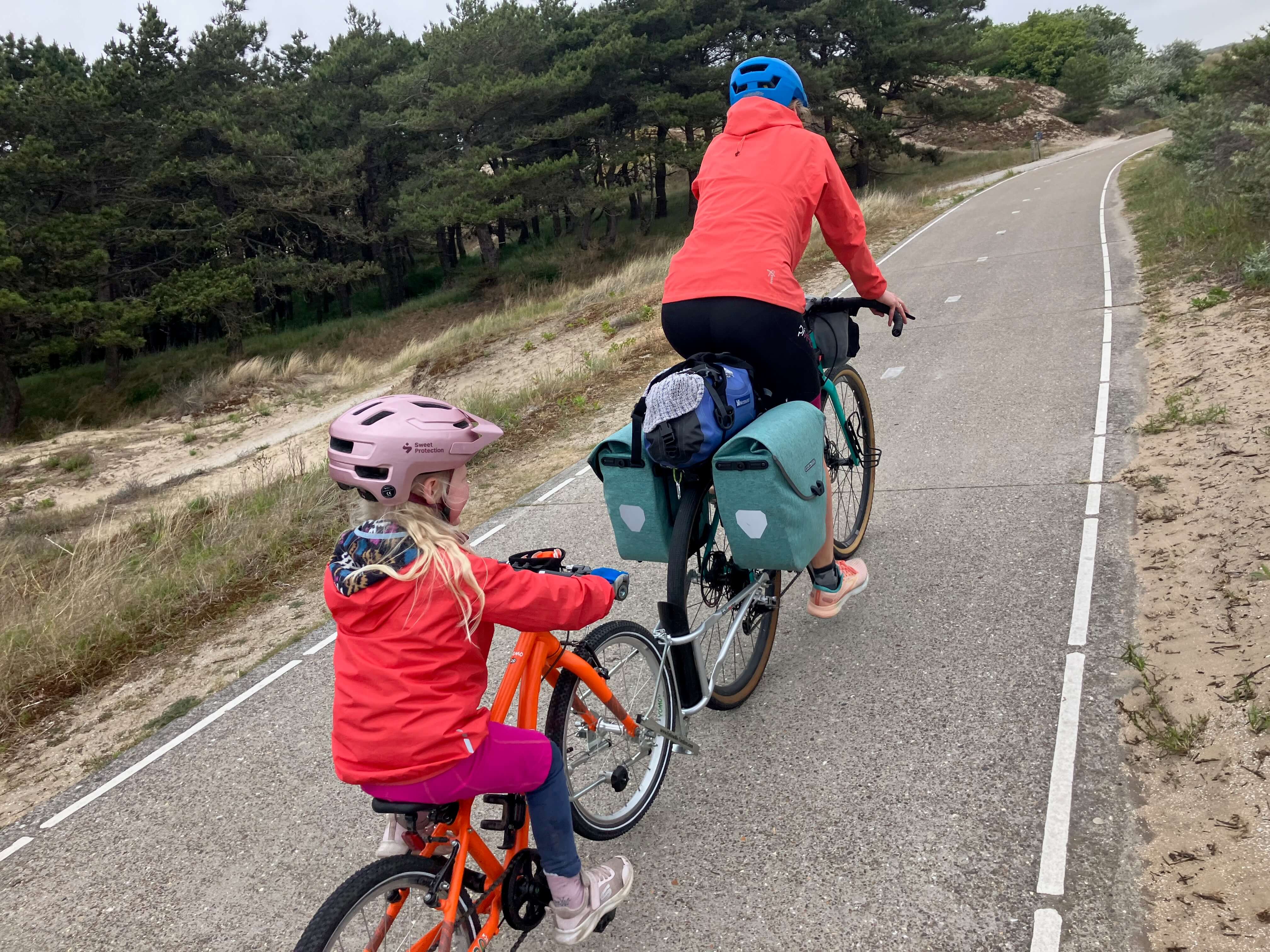 Child being towed with a FollowMe Tandem set up attached to an adults bike cycling along a country road in the Netherlands